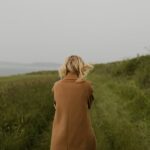 Anonymous woman walking in cold field
